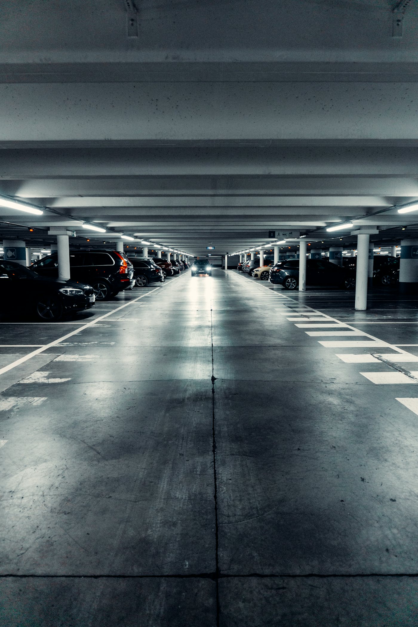 Sótano de estacionamiento de un corporativo, con cajones marcados y un coche entrando